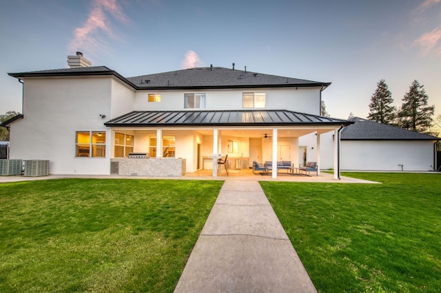 back of property featuring a yard, a standing seam roof, a patio area, and cooling unit