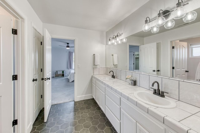 ensuite bathroom featuring tile patterned flooring, a sink, baseboards, and double vanity