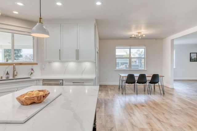 kitchen featuring a healthy amount of sunlight, tasteful backsplash, white cabinets, and a sink