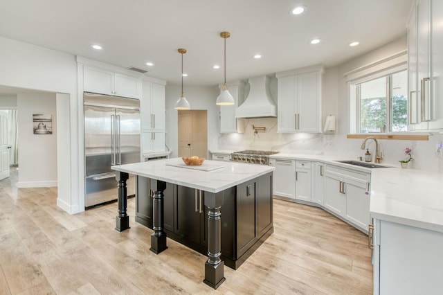 kitchen featuring a center island, a sink, stainless steel appliances, premium range hood, and backsplash