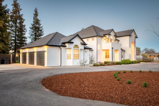 view of front of house featuring driveway, an attached garage, a balcony, and stucco siding