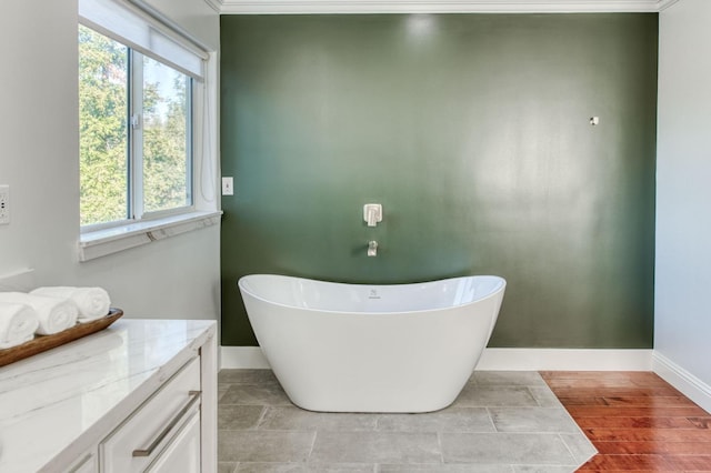 full bath with a freestanding tub, baseboards, wood finished floors, and vanity