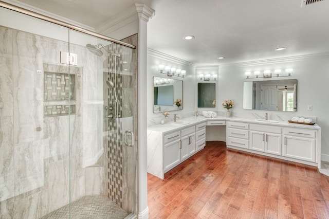 bathroom with ornamental molding, wood finished floors, vanity, and a shower stall