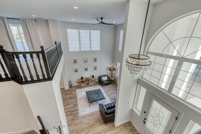 interior space featuring light wood-style floors, a high ceiling, baseboards, and recessed lighting