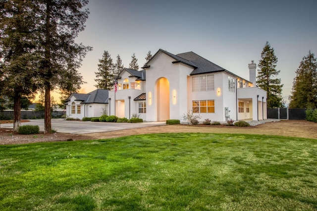 view of front facade featuring a front yard, fence, a chimney, and stucco siding