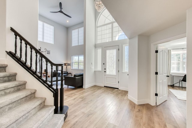 entryway with a high ceiling, stairway, wood finished floors, and baseboards