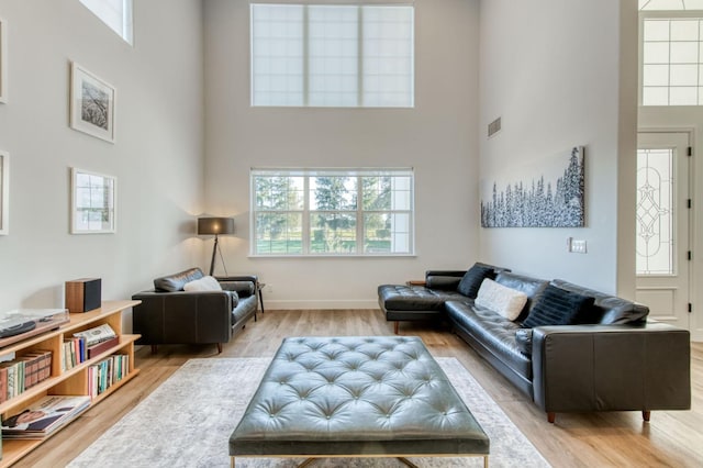 living room with baseboards, a high ceiling, visible vents, and wood finished floors