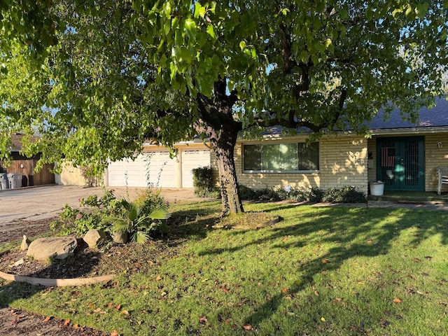 view of front of home featuring a garage, driveway, brick siding, and a front lawn