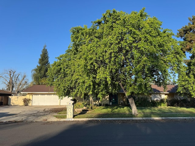 obstructed view of property with a garage, fence, a front lawn, and concrete driveway