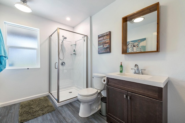 full bathroom featuring toilet, wood finished floors, vanity, baseboards, and a stall shower