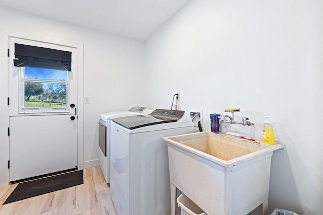 laundry room with light wood-style flooring, laundry area, a sink, baseboards, and washer and dryer