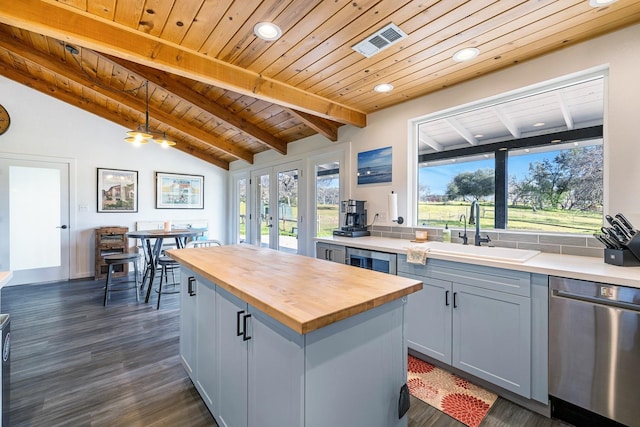 kitchen featuring visible vents, wooden counters, lofted ceiling with beams, stainless steel dishwasher, and a sink