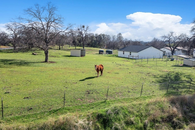 view of yard featuring an outbuilding, a rural view, and fence