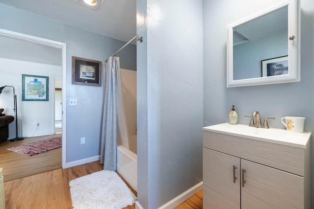 bathroom with shower / bath combo, vanity, baseboards, and wood finished floors