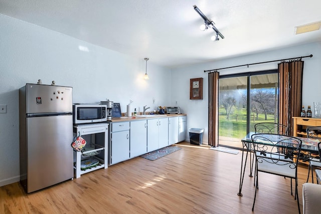 kitchen with stainless steel appliances, visible vents, white cabinetry, a sink, and light wood-type flooring