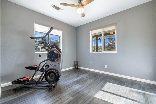 exercise room featuring visible vents, ceiling fan, baseboards, and wood finished floors