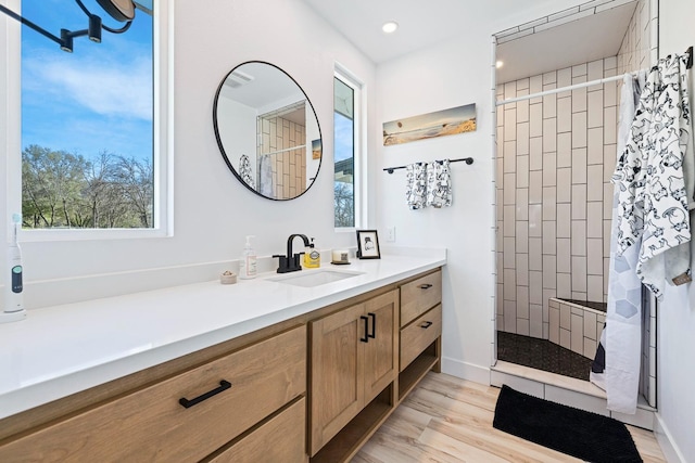 bathroom with recessed lighting, wood finished floors, vanity, and walk in shower