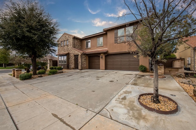 traditional-style house with a garage, driveway, stone siding, fence, and stucco siding