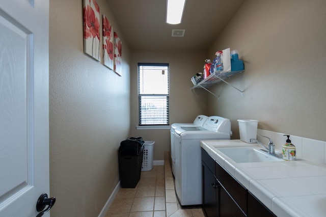 laundry room featuring cabinet space, light tile patterned floors, baseboards, separate washer and dryer, and a sink