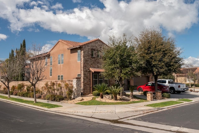 view of front of property featuring driveway, stone siding, and stucco siding