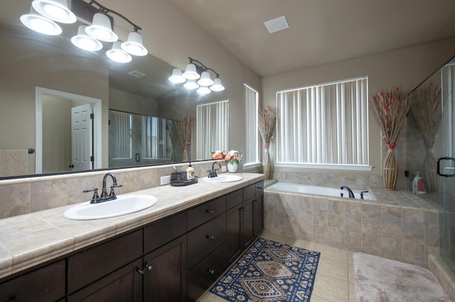 bathroom featuring a bath, double vanity, a sink, and tile patterned floors