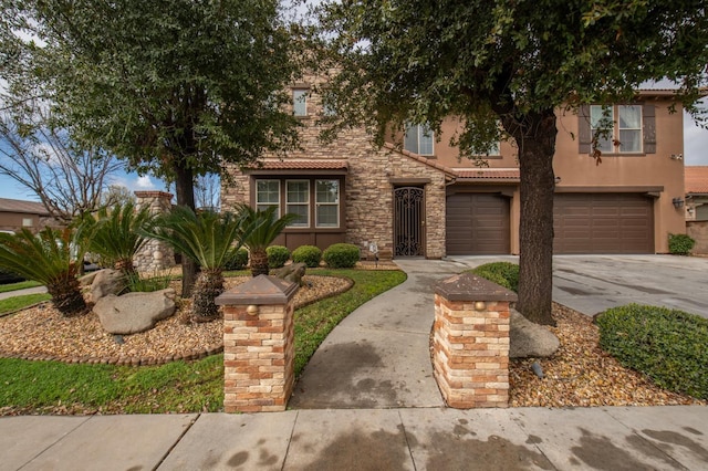 view of front of property featuring driveway, stone siding, an attached garage, and stucco siding