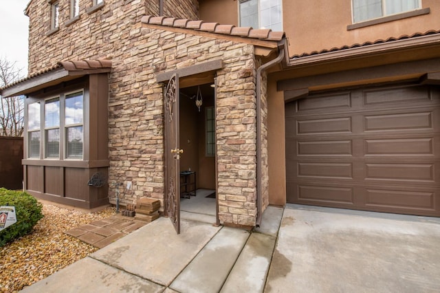 view of exterior entry featuring a garage, stone siding, and a tiled roof