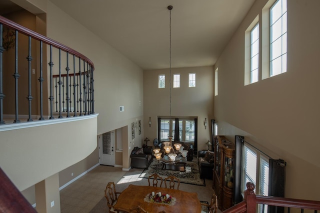 living area with stairs, plenty of natural light, a towering ceiling, and baseboards