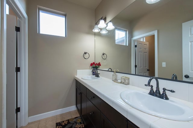 bathroom with double vanity, baseboards, a sink, and tile patterned floors