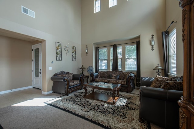 living area featuring a wealth of natural light, baseboards, visible vents, and a high ceiling