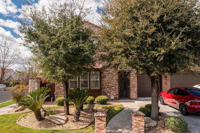 obstructed view of property featuring a garage, stone siding, and driveway