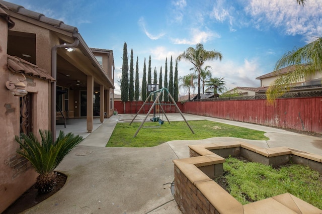 view of yard featuring a patio area, a fenced backyard, a ceiling fan, and a playground