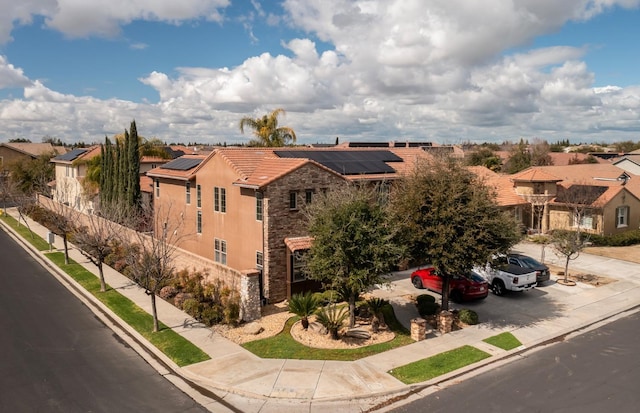 view of front of property featuring a residential view, stone siding, roof mounted solar panels, and stucco siding