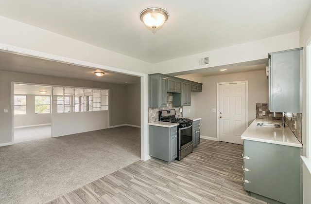 kitchen featuring a sink, visible vents, light countertops, gray cabinets, and stainless steel gas stove