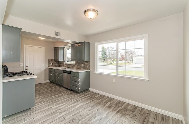 kitchen featuring gray cabinets, light countertops, visible vents, backsplash, and stainless steel dishwasher