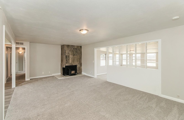 unfurnished living room with carpet floors, visible vents, and baseboards