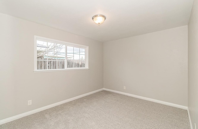 carpeted empty room featuring baseboards