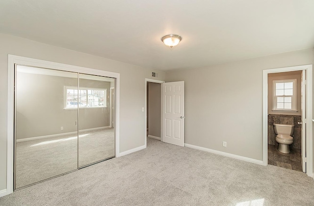 unfurnished bedroom with carpet, a closet, visible vents, and ensuite bathroom