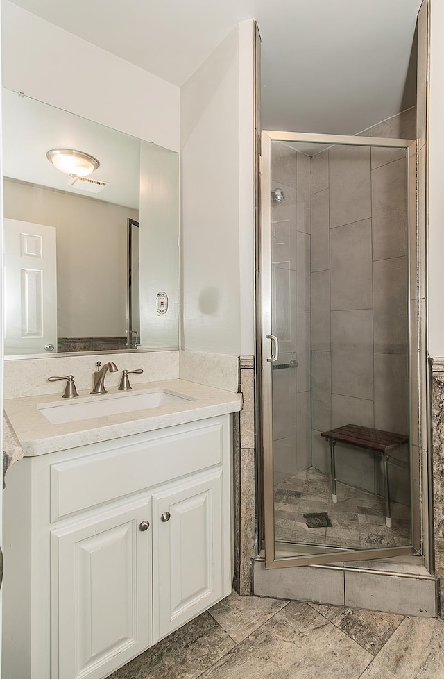 bathroom with visible vents, a shower stall, and vanity