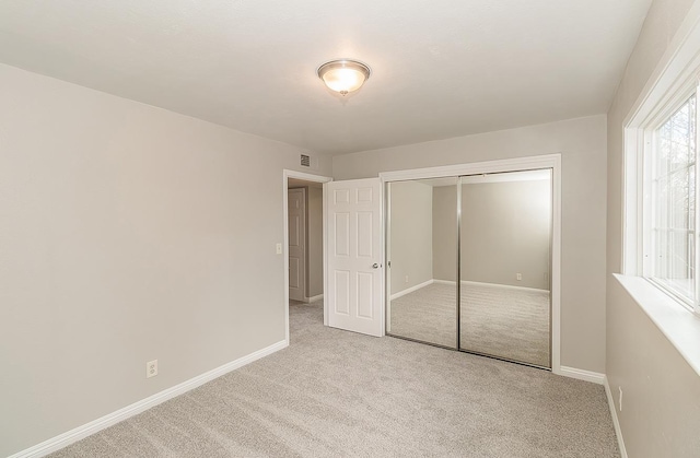 unfurnished bedroom with a closet, carpet flooring, visible vents, and baseboards