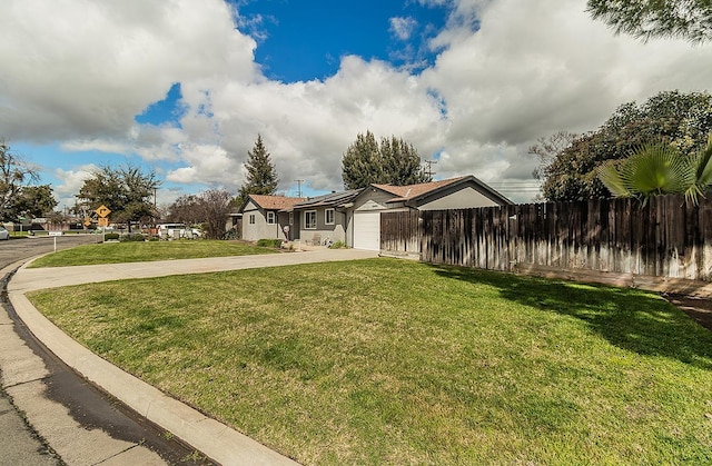 view of front of home featuring concrete driveway, a front lawn, an attached garage, and fence