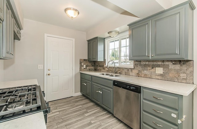 kitchen featuring light countertops, a sink, stainless steel dishwasher, and gas range oven