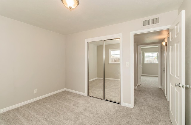 unfurnished bedroom with carpet floors, a closet, visible vents, and baseboards