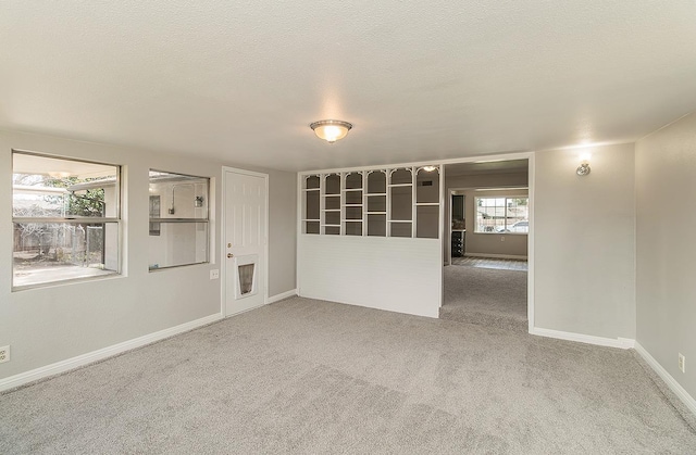 carpeted empty room with a textured ceiling and baseboards