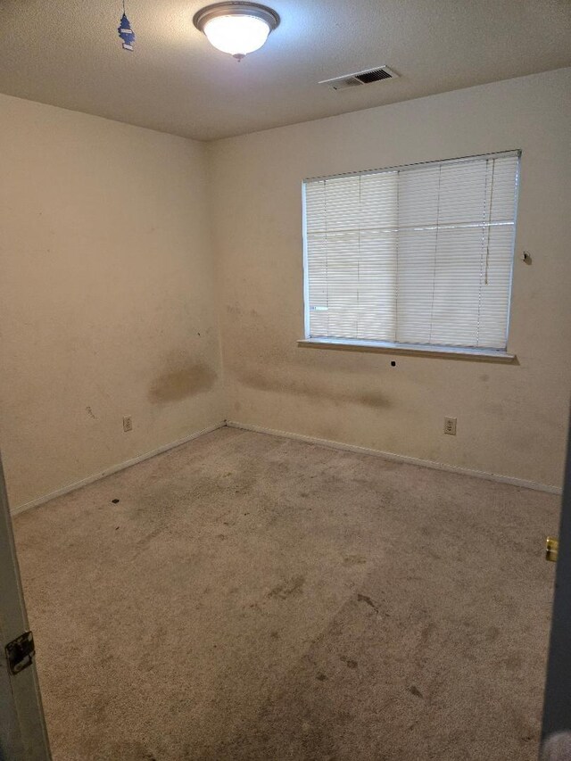spare room featuring baseboards, visible vents, and carpet