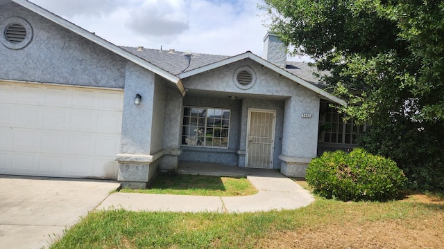 view of front of home featuring an attached garage, a chimney, roof with shingles, and stucco siding