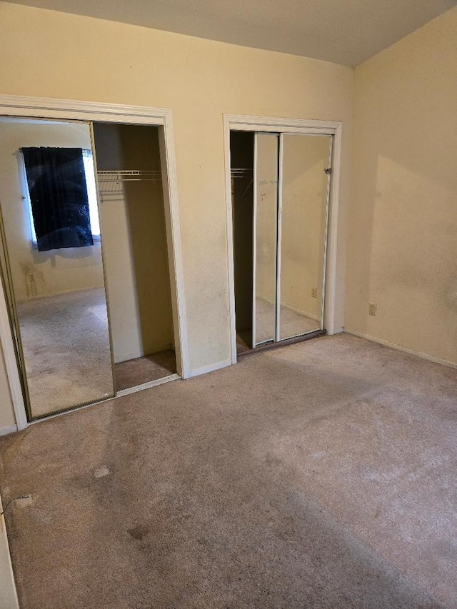 unfurnished bedroom with carpet flooring and multiple closets