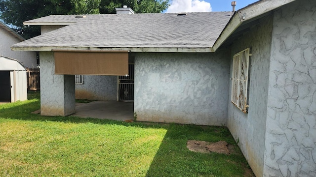 exterior space with roof with shingles, a chimney, stucco siding, and a lawn