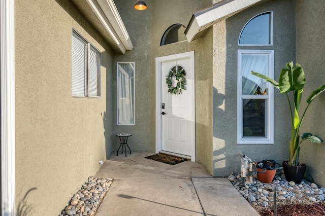 view of exterior entry featuring a patio area and stucco siding