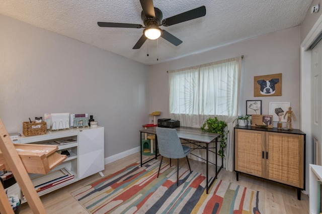 office with light wood-type flooring, baseboards, and a textured ceiling